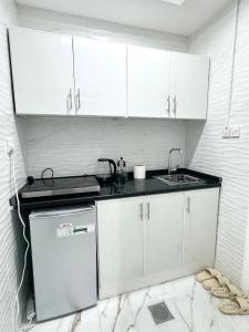 a small kitchen with white cabinets and a sink at Velmora Villas room 14 in Abu Dhabi