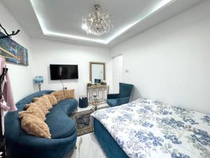 a bedroom with a blue couch and a tv at Velmora Villas room 14 in Abu Dhabi