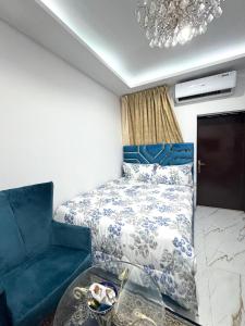 a bedroom with a bed and a blue chair at Velmora Villas room 14 in Abu Dhabi +4 photos