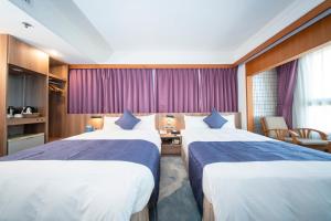 two beds in a hotel room with purple curtains at Foung Jia Hotel in Magong +21 photos