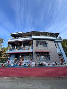 a building with a balcony with chairs on it at Living Roots Lodge in Cherrapunji