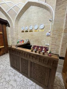 a lobby with a counter with clocks on the wall at Turkman Madrasah XIX Century Hotel in Bukhara