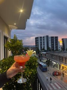 a person holding a drink on a balcony at Hotel Monaco in Kamëz
