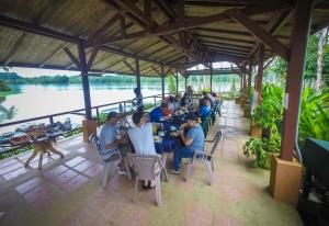 a group of people sitting at tables in a restaurant next to a river at Lirio Lodge in Barra de Pacuare +42 photos
