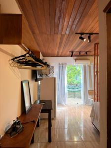 a living room with a wooden ceiling and a table at Pituba Vile - Apartamento Jardim in Itacaré