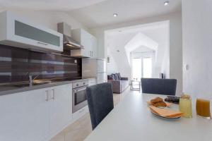 a white kitchen with a table with chairs and a sink at Apartments Kutlic in Cavtat