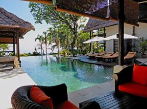 a pool at a resort with chairs and tables at Villa Terang Bulan - luxury private beachfront villa in Pengastulan