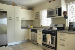 uma cozinha com armários brancos e um forno com placa de fogão em Mermaid Apartments em Saint Philip