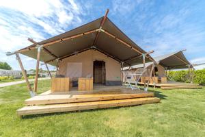 a large tent with a deck in a field at Camping de Haas in Wolphaartsdijk