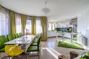 een keuken en eetkamer met een tafel en groene stoelen bij Villa Maja in Varna