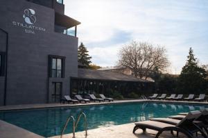 a swimming pool with chaise lounge chairs next to a building at Stillaterm SPA in Mineralni Bani