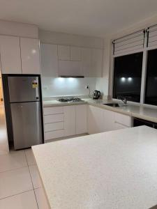 a kitchen with white cabinets and a stainless steel refrigerator at island payless private room in Nadi +12 photos
