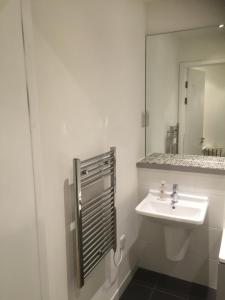 a white bathroom with a sink and a mirror at RA Service Apartment in London