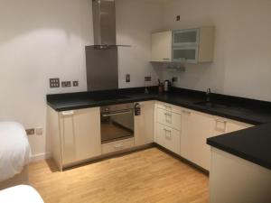 cocina con armarios blancos y encimera negra en RA Service Apartment, en Londres