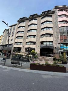 a large building with a bench in front of it at Aparthotel El Serch in Andorra la Vella