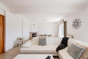 a white living room with a white couch and a fireplace at Lisbon Coastal Retreat in Charneca