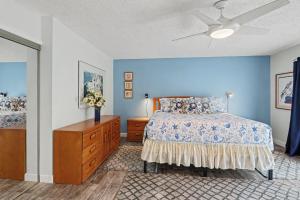 a bedroom with blue walls and a bed and a dresser at Land's End 8-301 Beach Front in St. Pete Beach