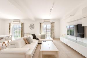 a white living room with a white couch and a tv at Lisbon Coastal Retreat in Charneca