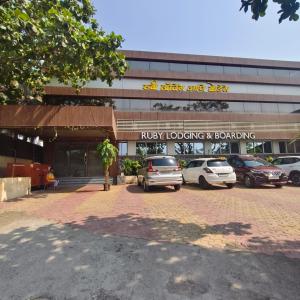 a building with cars parked in a parking lot at Ruby Lodging And Boarding in Mangrul