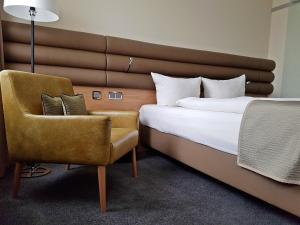 ein Hotelzimmer mit einem Bett und einem Stuhl in der Unterkunft Hotel Ross in Schweinfurt