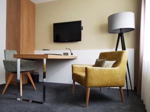 ein Zimmer mit Schreibtisch, Stuhl und Fernseher in der Unterkunft Hotel Ross in Schweinfurt