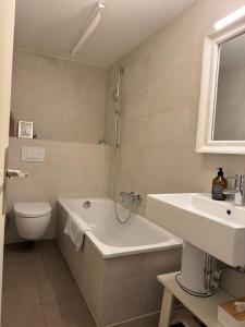 a bathroom with a tub and a toilet and a sink at Apartment Ammersee in Dießen am Ammersee +24 photos