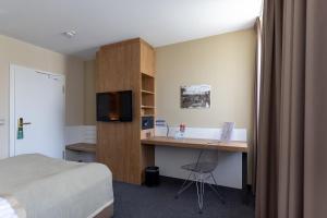 ein Hotelzimmer mit Schreibtisch und Bett in der Unterkunft Hotel Ross in Schweinfurt
