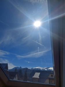 a window with a view of the sun in the sky at Pod skosem in Witów