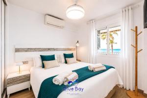 a white bedroom with two beds and a window at Shore Thing Playa in La Herradura