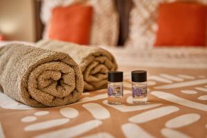 a bed with towels and two bottles of essential oils at Le Clos des Remparts - 8 pers - Cascades & Nature in La Plaine des Palmistes +40 photos