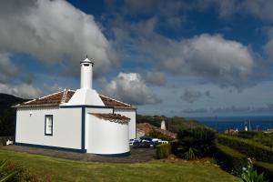 a white lighthouse on a grass field with the ocean at Casa do Norte - Santa Maria in Norte