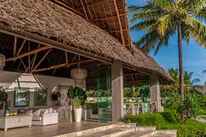 a resort with a straw roof with palm trees at Zawadi Hotel, Zanzibar in Michamvi