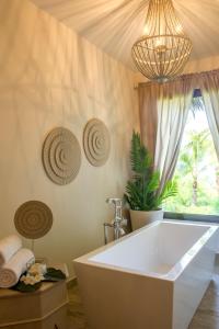 a bath tub in a bathroom with a chandelier at Zawadi Hotel, Zanzibar in Michamvi +46 photos
