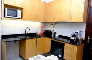 a small kitchen with wooden cabinets and a microwave at Gods Barn House in Viana do Castelo