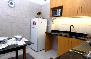 a kitchen with a white refrigerator and a sink at Gods Barn House in Viana do Castelo