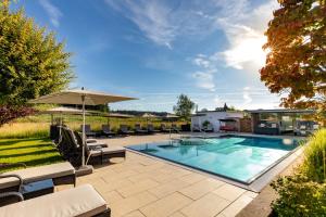 a swimming pool with chairs and an umbrella at Hotel Gierer in Wasserburg