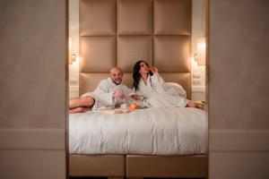 a man and woman sitting on a bed talking on a cell phone at Ponte Vecchio Suites & Spa in Florence