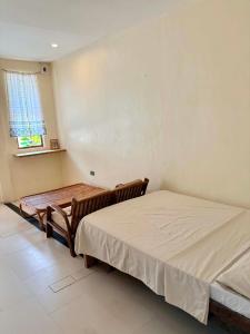 a bedroom with two beds and a table and a window at Ayu Homestay - Room 3 in San Isidro