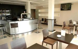 a restaurant with a bar with tables and chairs at Hotel Arteixo in Arteixo