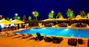 a swimming pool with chairs and umbrellas at night at Hotel Anaklia in Zugdidi