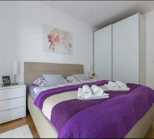 Un dormitorio con una gran cama púrpura con toallas. en Apartment Ali, en Zagreb