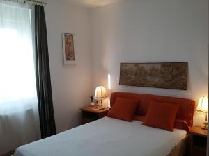 a bedroom with a bed with orange pillows and two lamps at GESZTENYÉS Vendégház in Harkány