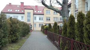 a walkway in front of a building with a tree at Apartament Monika Rewal z widokiem na morze in Rewal