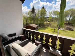 a balcony with chairs and a table and a green umbrella at Ferienwohnung Stella in Krün