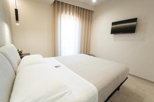 a bedroom with a white bed and a television at HERMES Luxury Home in Agrigento