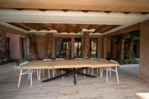 a large wooden table sitting in a patio at Villa bord du lac takerkoust marrakech , 9 Suites de Luxe & événementiel in Wawizelt