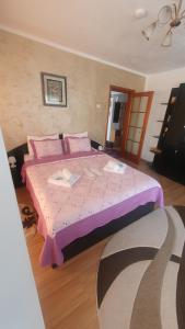 a bedroom with a large bed with a pink comforter at Apartament RHC in Târgu Ocna