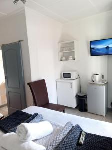 a room with a bed and a microwave and a kitchen at Lancaster Guest House in Boksburg