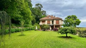 a house with a large yard with a tree at Hotel EntreRobles in Baiona