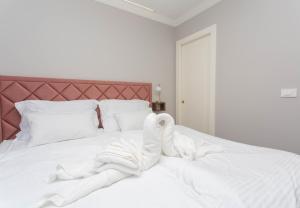 a white bed with a pile of towels on it at Luxury Rooms by Iva in Zadar